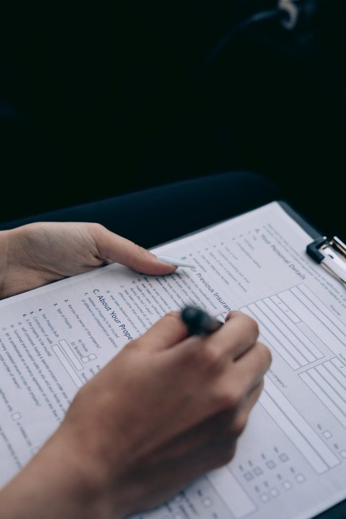 A persons hand writing on a form attached to a clipboard, highlighting data entry.